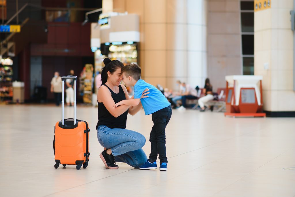 woman hugging a child in the airport with luggage nearby
