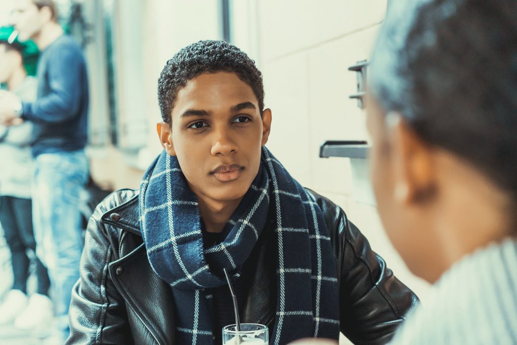 Adolescent male talking outside with a smoothie to an older mentor